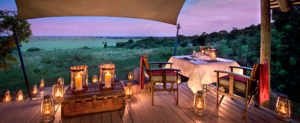 Romantic honeymoon safari dinner in Africa with lanterns and savannah backdrop.