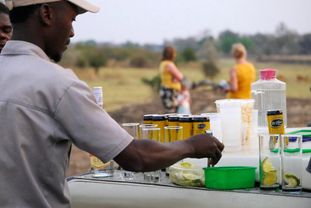 Couple enjoying sundowner drinks on African safari with elephants in the distance
